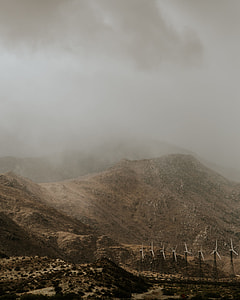 white windmills beside mountain under gray cloudy sky thumbnail