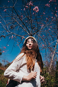 woman holding backpack strap under flowering tree thumbnail