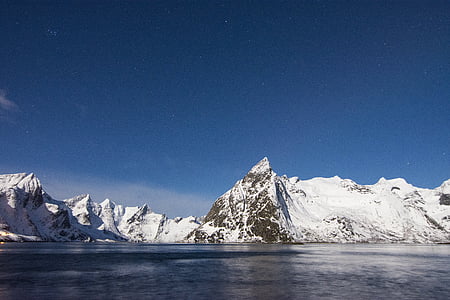 snow-covered mountain beside ocean during daytime thumbnail