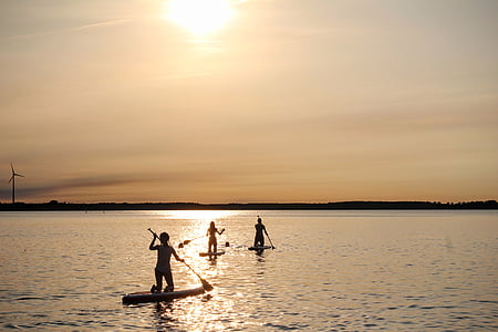 three people riding paddle board under golden hour thumbnail