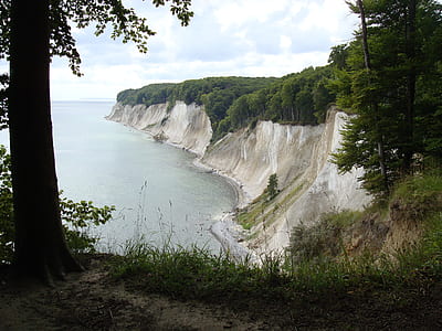 gray cliff beside body of water thumbnail