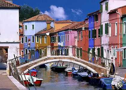 boat under arch bridge on a canal near assorted-color concrete houses thumbnail