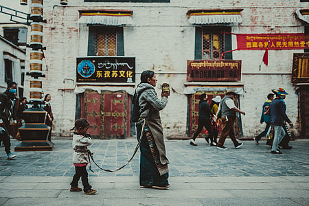 child and mother walking beside concrete building thumbnail