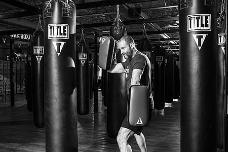 man facing heavy bag holding training gloves thumbnail