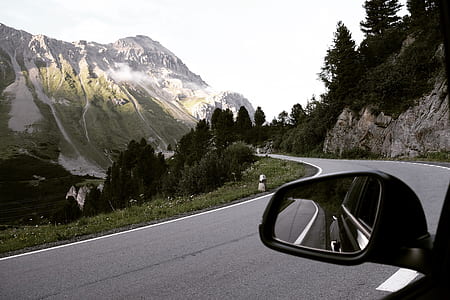 car at the road in a distance of a mountain and trees thumbnail