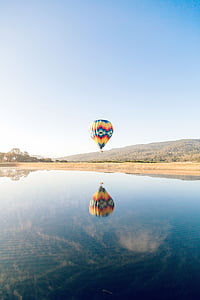 yellow and blue hot air balloon over calm body of water thumbnail