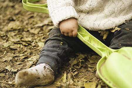 toddler sitting on ground while holding green plastic garden shovel thumbnail