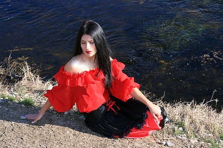 woman wearing red and black dress sitting near sea water during daytime thumbnail