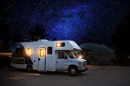 white RV beside the shore under blue and black skies thumbnail