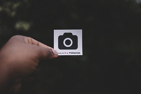 person holding white and black camera print paper thumbnail