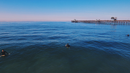 three person on body of water near sea dock thumbnail