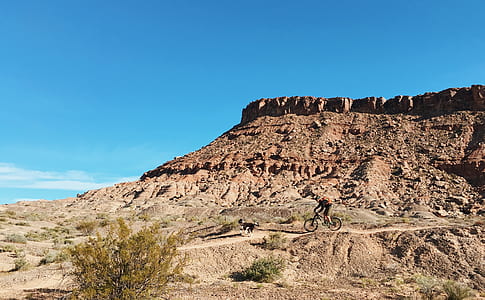 person cycling near on brown mountain cliff thumbnail