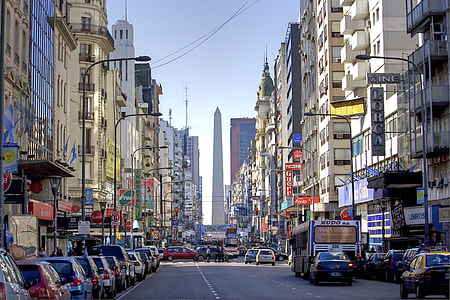 assorted vehicles on asphalt road surrounded concrete buildings thumbnail