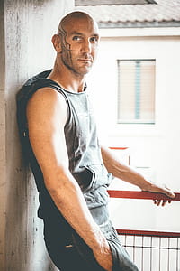 Man in Black Sleeveless Hoodie Leaning on Gray thumbnail