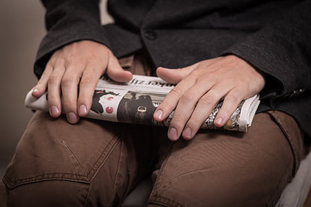 person holding newspaper place on lap thumbnail