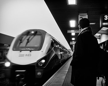 grayscale photo of person standing near train thumbnail