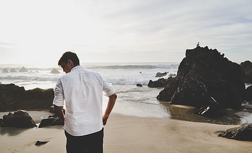 man in white dress shirt standing in front of beach during daytime thumbnail