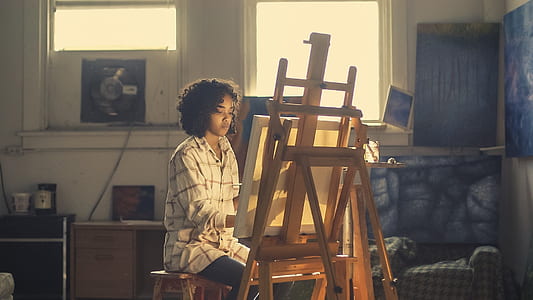 woman wearing white sport shirt painting on canvas while using easel thumbnail
