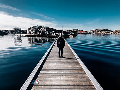 person standing on brown wooden dock during daytime thumbnail
