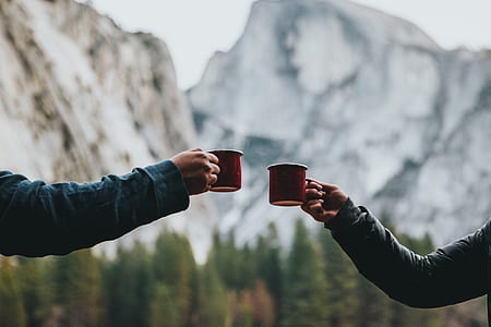 two persons holding red ceramic mugs thumbnail