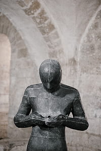 black concrete statue standing near wall thumbnail