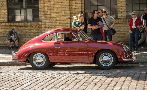 man on classic red coupe parked near people thumbnail
