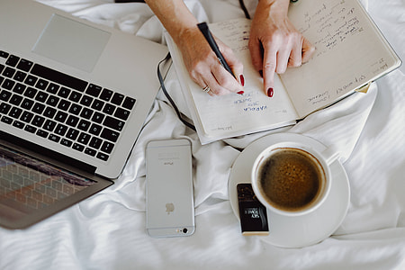 Woman working on a laptop while enjoying a breakfast coffee and chocolate in bed thumbnail