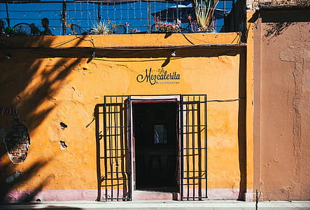 Entrance of a tropical bar with yellow exterior and wrought iron gate thumbnail