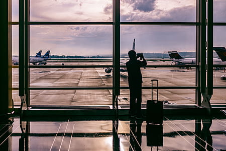 silhouette of person stands beside luggage at airport thumbnail
