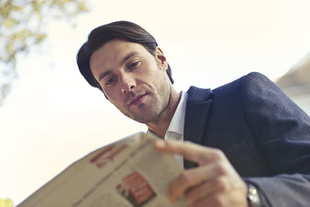 man wearing black blazer reading newspaper thumbnail