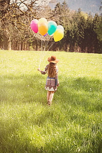 woman in brown and blue dress holding balloons thumbnail