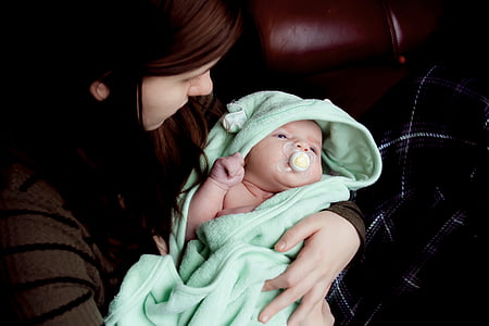 woman holding baby covered by green textile thumbnail