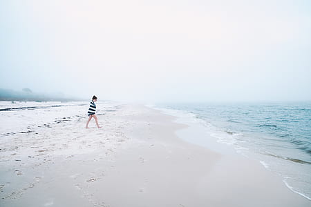 woman walking on beach during daytime thumbnail