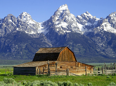 brown wooden barn near the snow capped mountains under the blue sky thumbnail