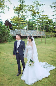 Couple Standing While Wearing Wedding Suits and Dress Near Gray Building thumbnail