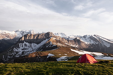 red dome tent near brown and white mountains at daytime thumbnail