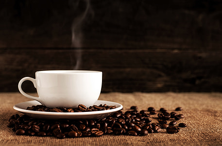 white teacup on top of saucer beside coffee beans thumbnail