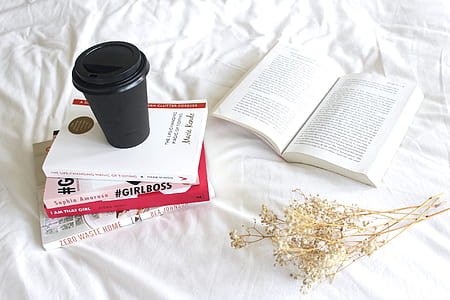 black spill-proof mug on pile of four books beside opened book thumbnail