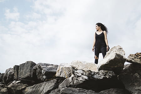 woman wearing black sleeveless dress standing on a rock thumbnail