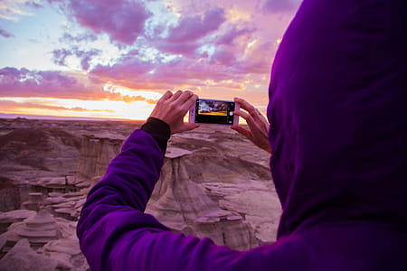 Person Wearing Purple Hoodie Jacket Holding Iphone 6 during Golden Hour thumbnail