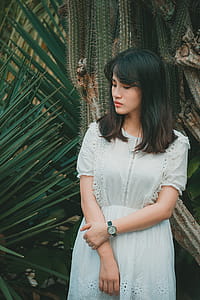 Woman Wearing a Teal Half-sleeved Dress standing Beside Green Plant thumbnail