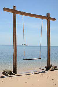 brown wooden swing on seashore thumbnail