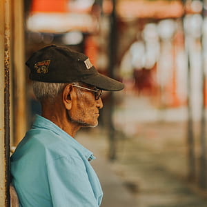 shallow focus photography of man wearing blue top and black baseball cap thumbnail