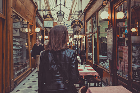 girl on leather jacket walking between cafe's thumbnail