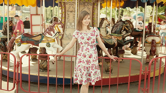 woman in white and pink floral dress near carousel thumbnail