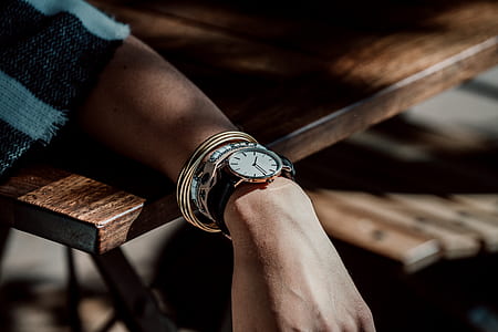 person wearing black watch lean hand on brown table thumbnail