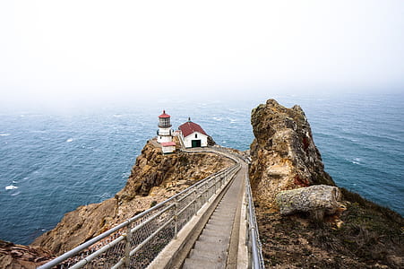lighthouse on cliff beside ocean thumbnail