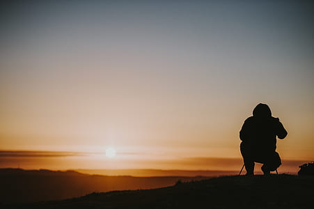 silhouette of person sitting on hill thumbnail