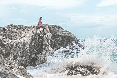 person sitting on rock beside body of water thumbnail