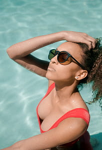 woman on pool wearing swimsuit and sunglasses during day time thumbnail